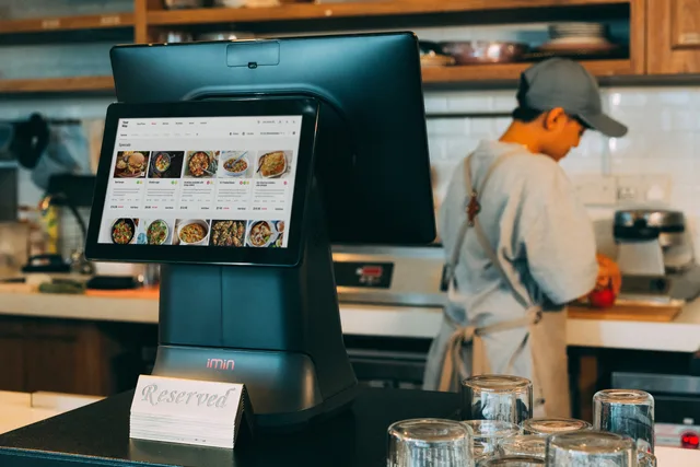Digital ordering system in a restaurant kitchen with a touchscreen display and a chef at work. When to build a food creator partnerships reporting dashboard