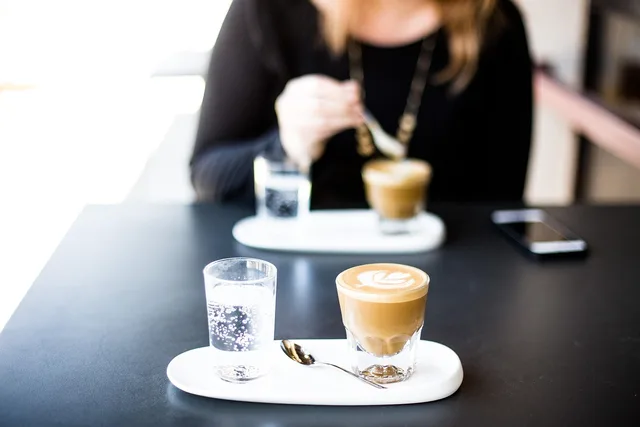 cafe, coffee cup, bar, restaurant, coffee, breakfast, cappuccino, cup, drink, glass, indoors, latte, person, plate, table. Food influencers' partnership review methods