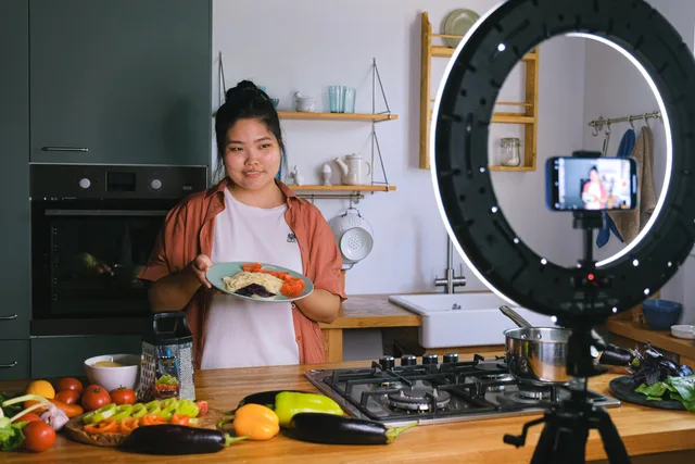 A woman demonstrates cooking in a stylish kitchen while filming content. Perfect for culinary and lifestyle themes. Seven tests for food creator partnerships reviews